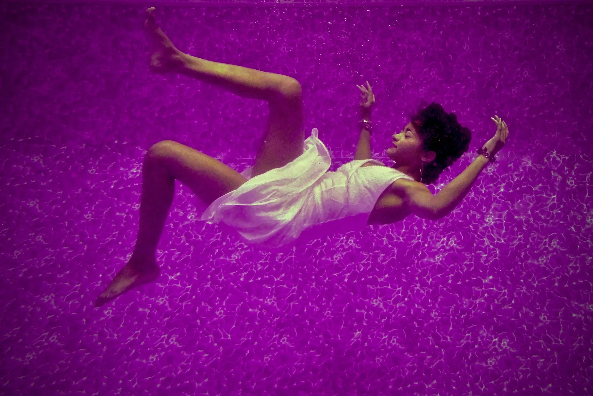 A woman in a white dress falling into a purple liquid